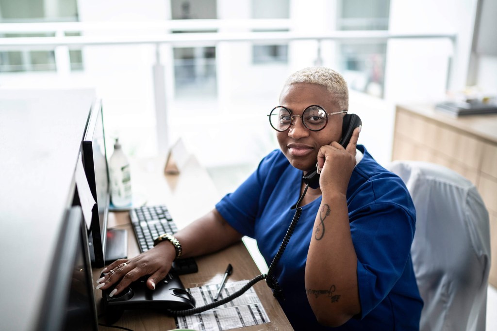 A medical office assistant talking on a phone